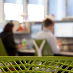 Camera shot peering from behind staff members at workstations