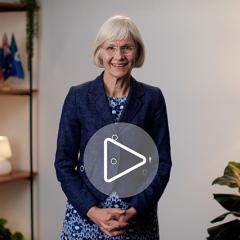 Professor Deborah Terry, UQ Vice-Chancellor, sitting down and smiling. A play button has been digitally added to the middle of the image.